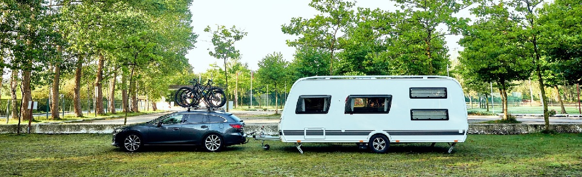 Bil og campingvogn på grønn plen