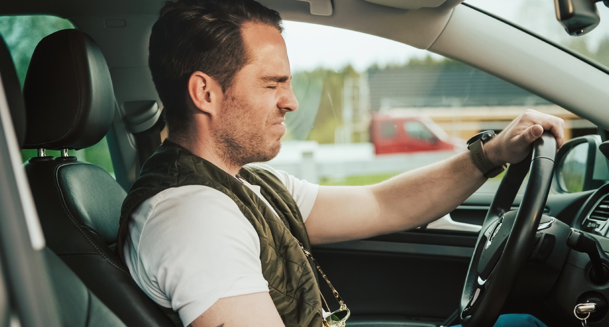 Mann griner på nesen over vond lukt i bilen sin. Han trenger en service på klimaanlegget