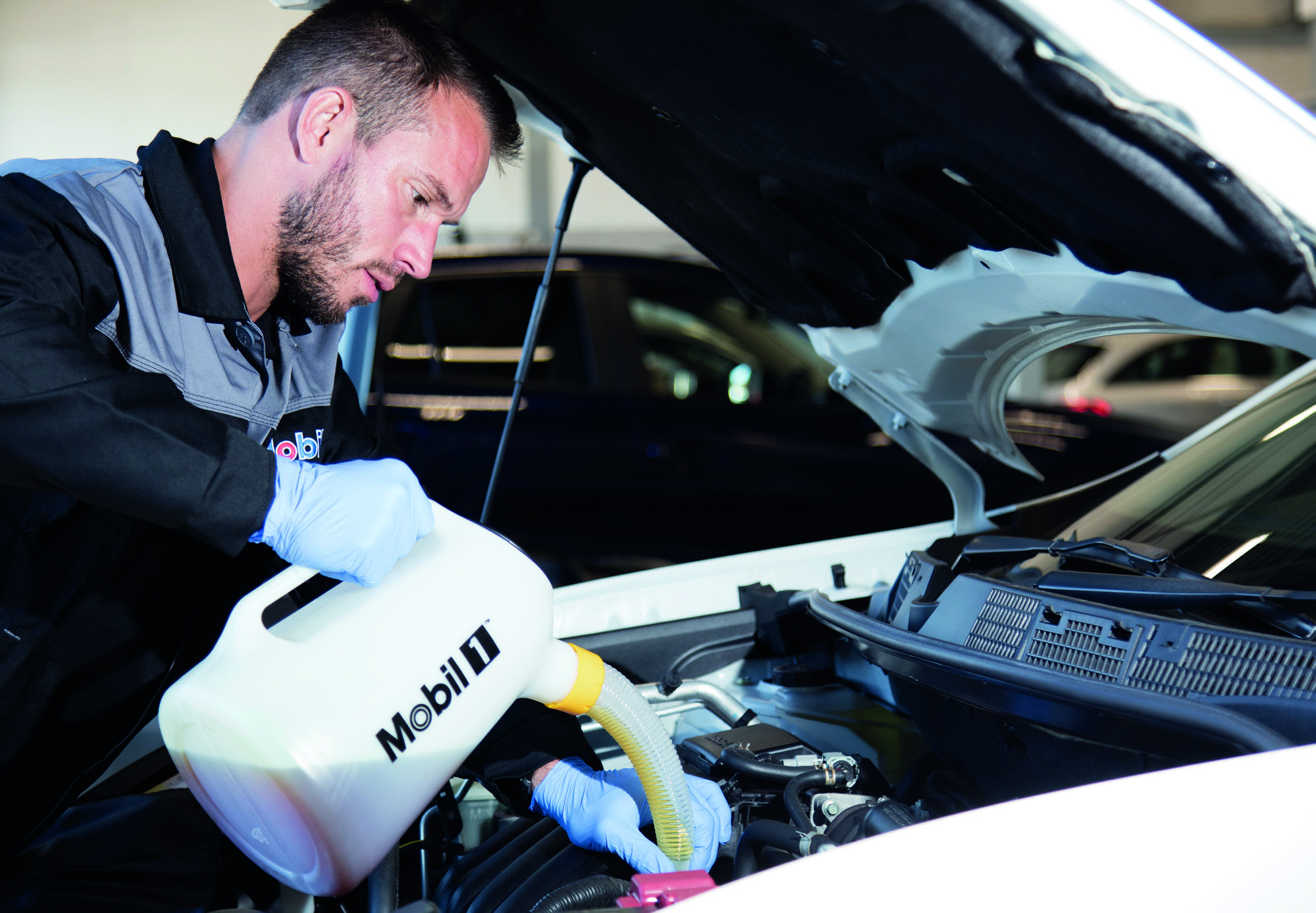Mekaniker fyller olje på bil med Mobil1 oljekanne