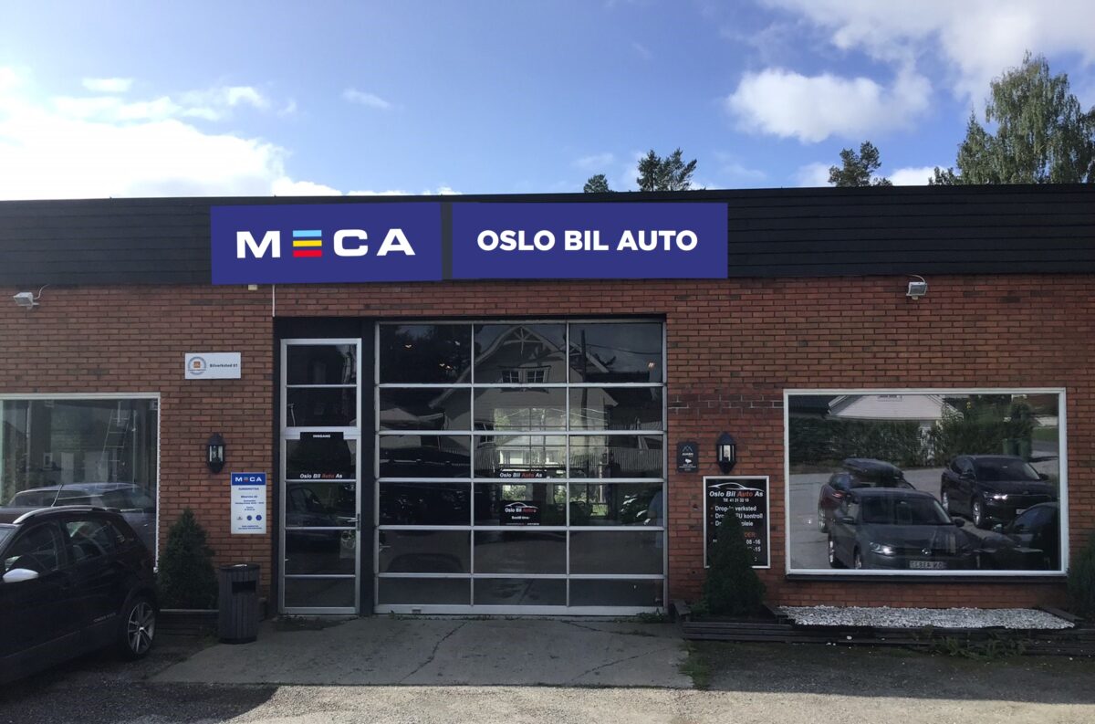 Bilverksted med MECA-skilt, Oslo Bil Auto, omgitt av biler og trær.