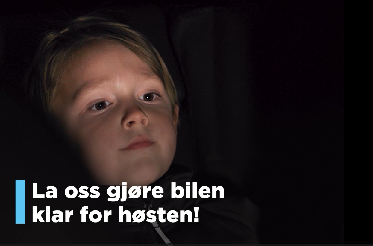 Liten gutt titter ut av bilen i mørket