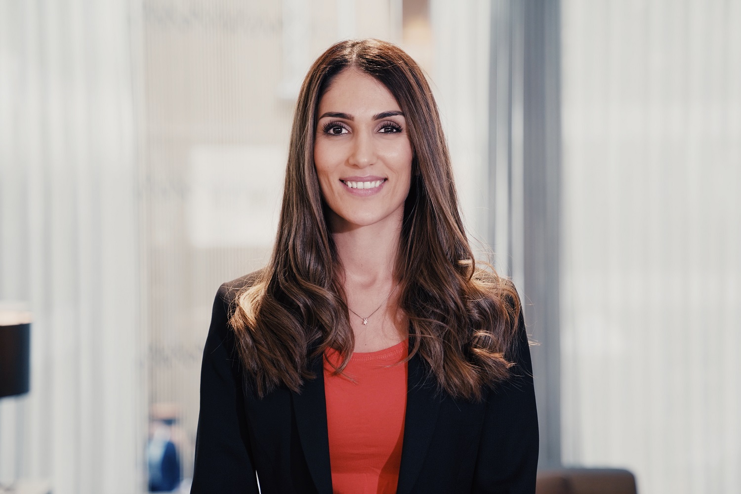 Profilbilde av en dame med mørkt hår, rød t-shirt og svart blazer