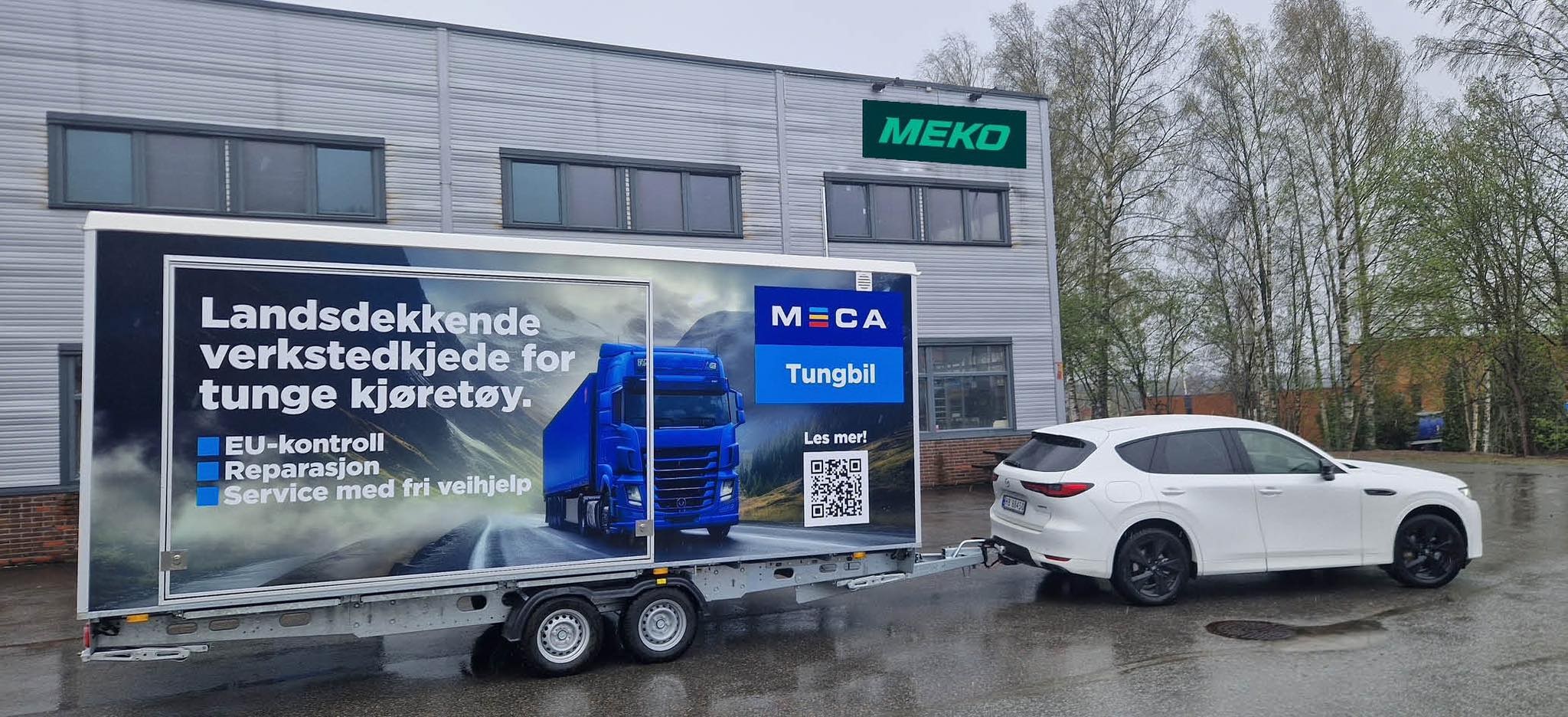 MECA Tungbil tilhengeren bak en hvit personbil foran ett grått MEKO lagerbygg