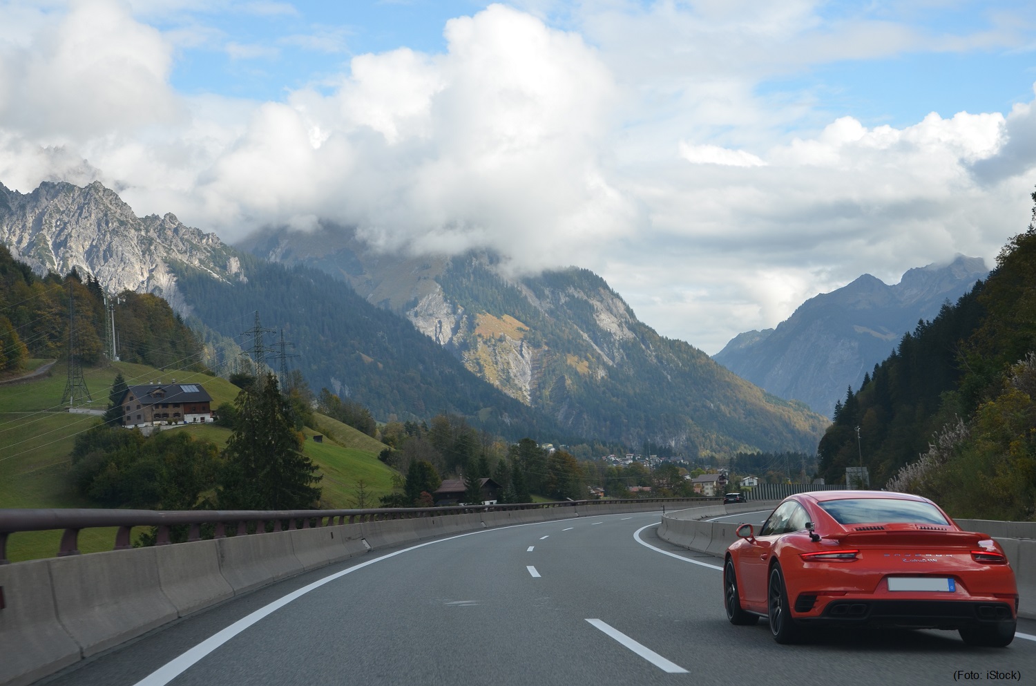 Rød Porsche kjører på fine motorveier med nydelig utsikt over fjellene i Østerrike