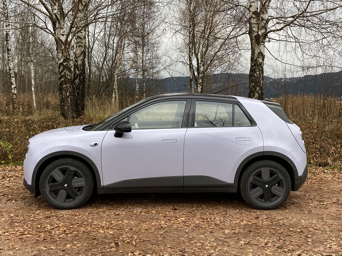 Hvit Firefly fra Nio parkert i skogen på høsten