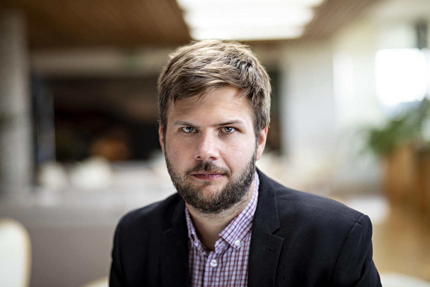 Profilbilde av en mann med mørkt hår, skjegg og bart med mørk dress og grå skjorte