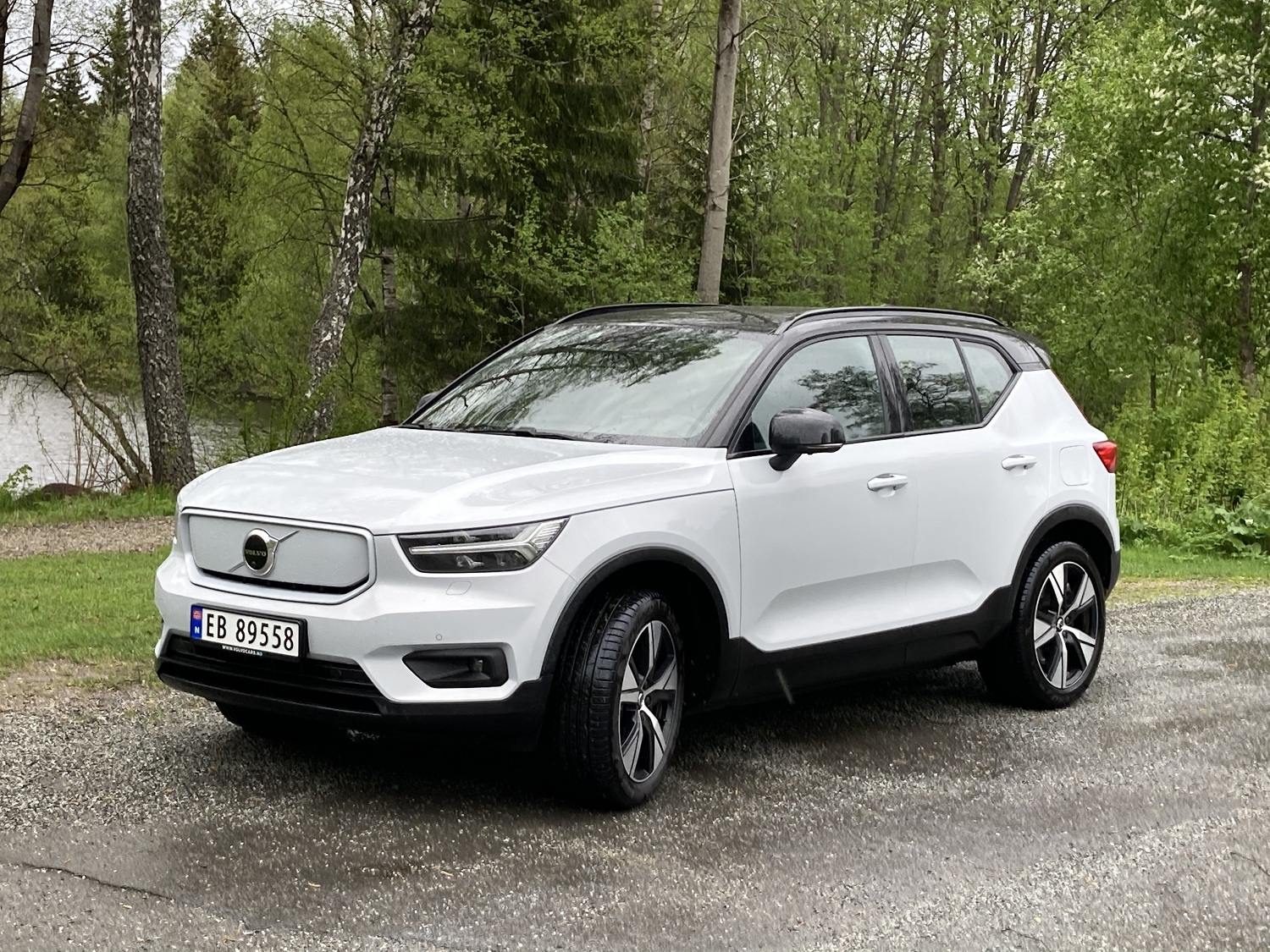 Hvit Volvo EX40, parkert i skogen