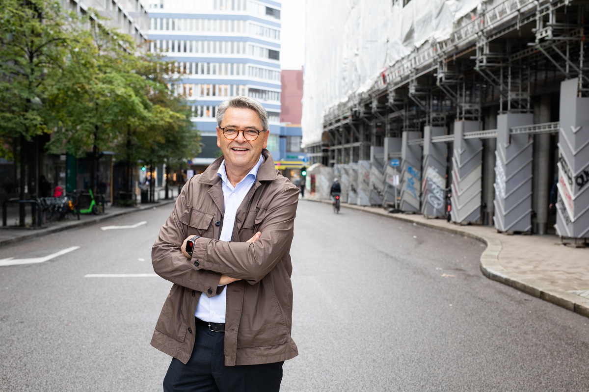 Mann med briller står på gaten med kryssede armer