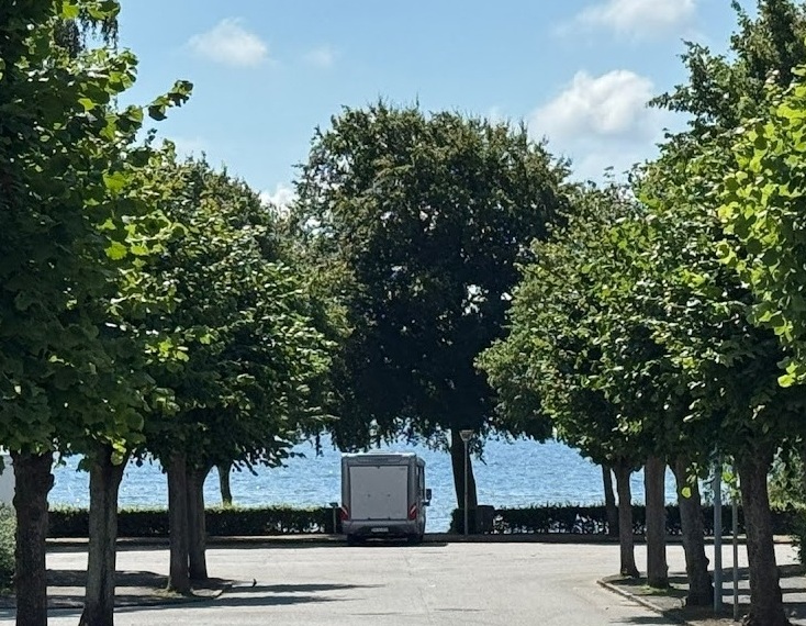 Bobil parkert i gønne omgivelser ved sjøen