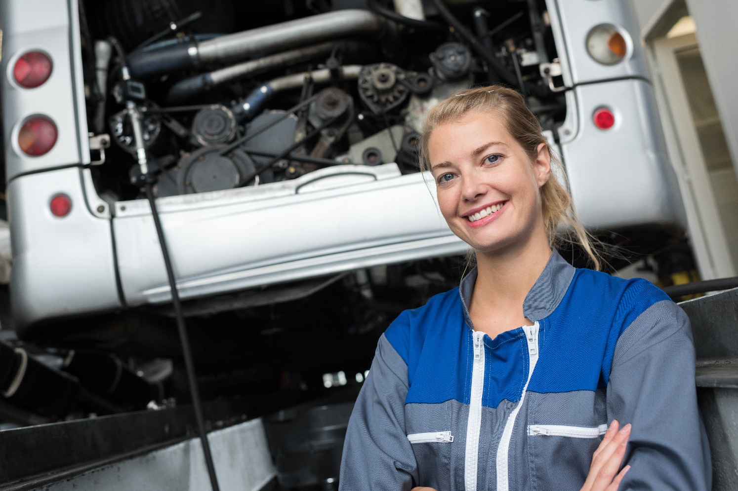 Kvinnelig mekaniker foran en bobil inne på verksted