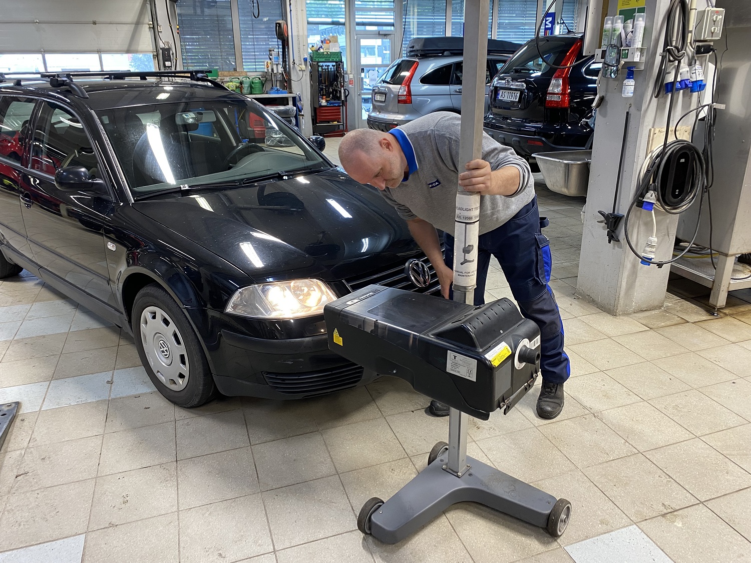 Mekaniker sjekker lysene på en svart bil, inne på verkstedet
