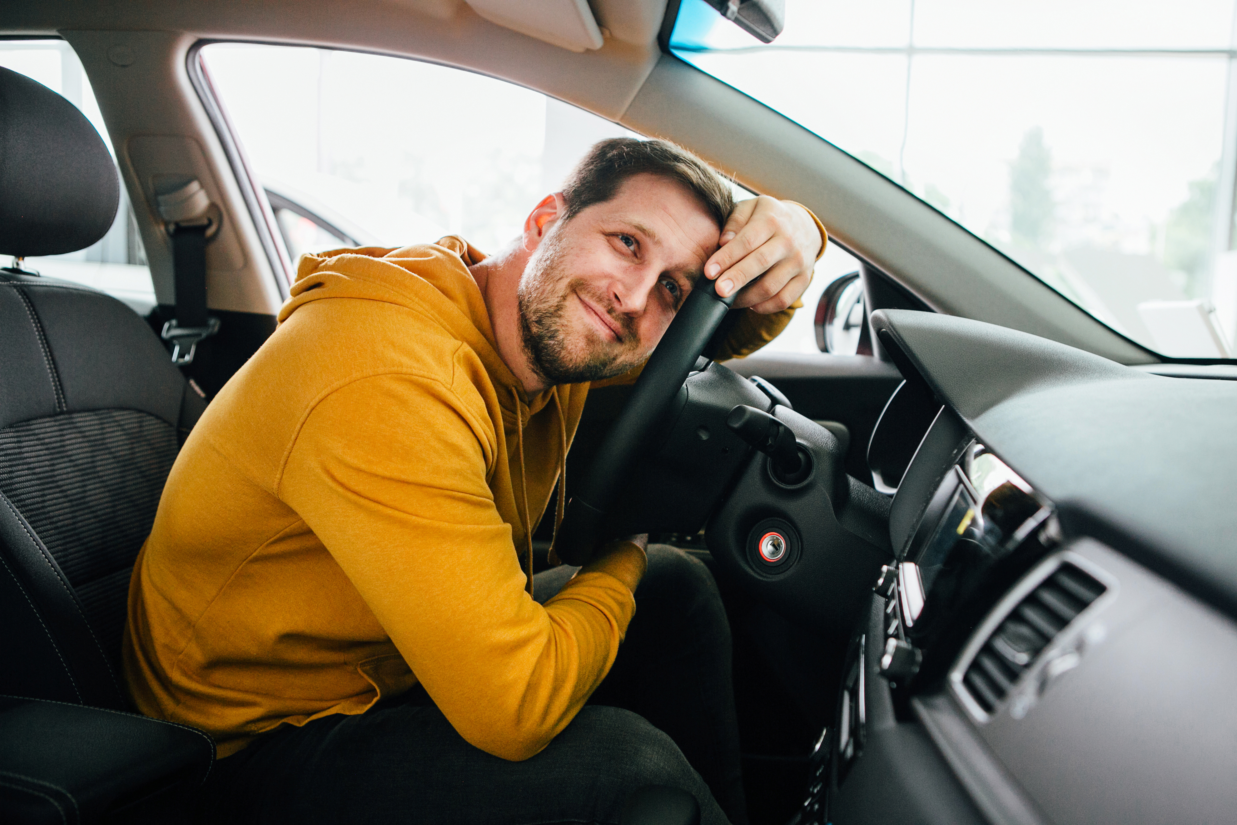 MAnn med gul genser sitter i bilen sin